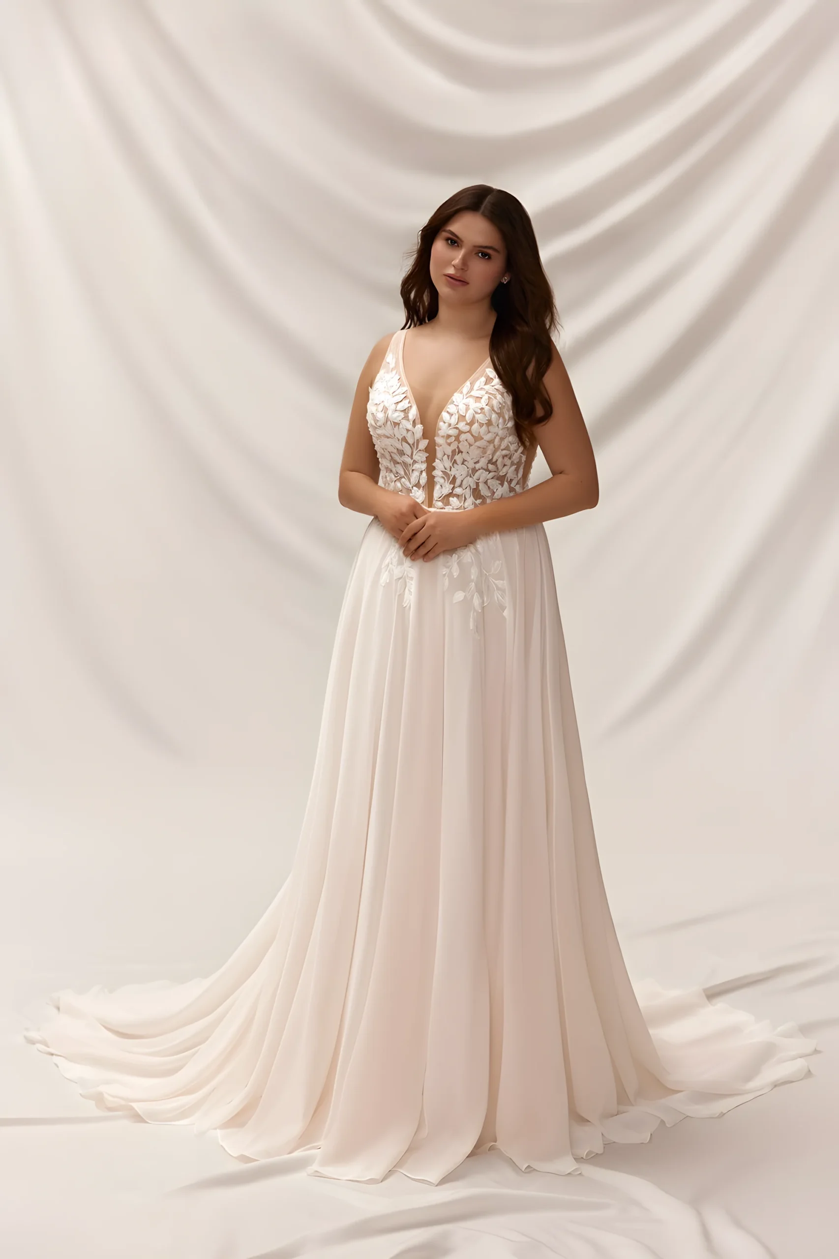 Robe de Mariée adaptée en grande taille avec un col en V profond et une jupe mousseline coupe A pour un tombé fluide.